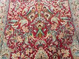 an oriental rug with birds and flowers on a red ground