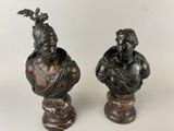 pair of bronze busts of a man and a woman with a bird on their head