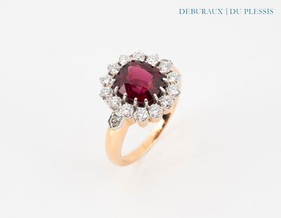 gros plan d'une bague avec une pierre rouge entourée de diamants