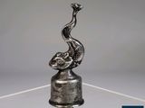 a silver sculpture of a bird on a glass base