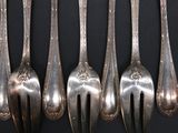 six silver spoons are lined up on a black surface