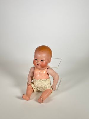 une petite poupée assise sur une chaise transparente