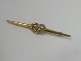 a close up of a gold tie bar on a white surface