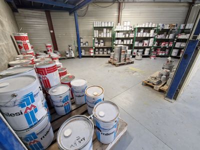 plusieurs seaux de peinture posés sur une palette dans un entrepôt