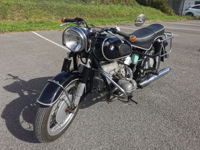 a black motorcycle parked in a parking lot next to a grassy hill