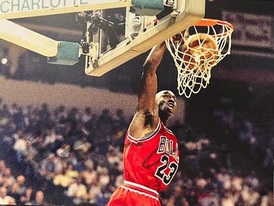 un joueur de basket-ball effectuant un dunk devant un panier, devant un public