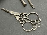 a pair of scissors sitting on a table next to a pair of scissors