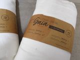 pair of white pillows on a couch with a brown tag on them