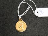 une médaille d'or suspendue à un cordon, avec une étiquette indiquant son prix