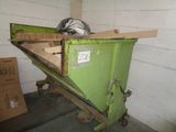 a green dumpster sitting in a room with boxes on the floor
