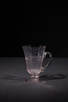 a glass cup sitting on a table with a black background