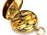 a gold pocket watch that is open on a white surface