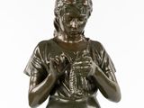 a bronze statue of a woman sitting on a stool