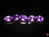 un groupe de pierres précieuses violettes posées sur une surface noire