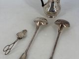 three silver spoons and a silver teapot on a table