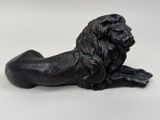 a black statue of a lion laying down on a white surface