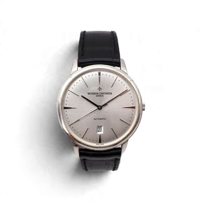 une montre argentée avec un bracelet noir posée sur une surface blanche