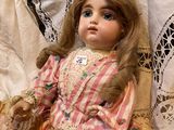 a doll that is sitting on a bed with a basket