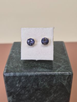 a close up of a pair of blue sapphire earrings on a marble block