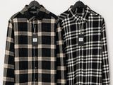 two men ' s shirts hanging on a hanger in front of a white wall