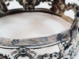 a close up of a silver crown on a white surface