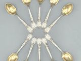 six cuillères en argent disposées en cercle sur une surface grise
