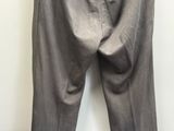 un pantalon gris suspendu à un cintre devant un mur blanc