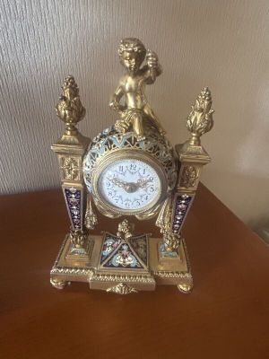 a clock on a table with a statue on top of it