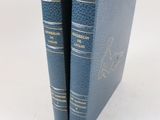 Deux livres bleus sont posés l'un sur l'autre sur une surface blanche.