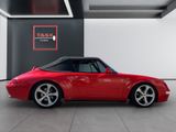 the red porsche 993 cab is parked in front of a black wall