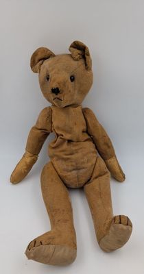 un ours en peluche marron assis sur une surface blanche