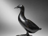 a black and white photo of a bird on a pedestal
