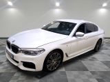 La berline BMW blanche est garée sur un sol en carrelage à damier.