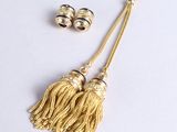 une paire de pompons dorés et une paire de boucles d'oreilles posés sur une surface blanche