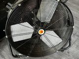 un ventilateur posé par terre à côté d'une valise
