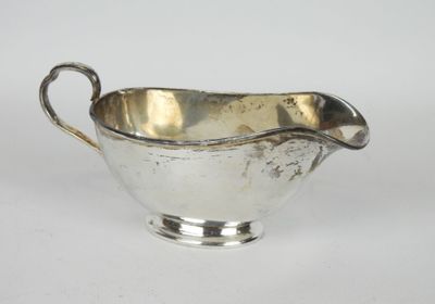 une saucière ancienne en métal argenté, dotée d'une poignée incurvée