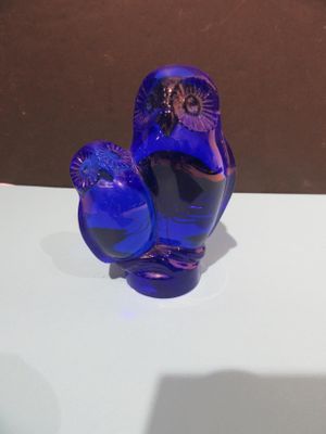 une figurine en verre bleu posée sur une table blanche