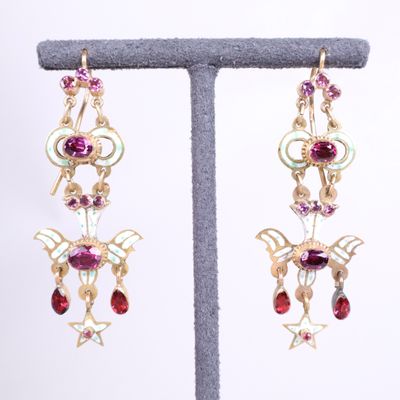 two pairs of earrings with garnets on a stand