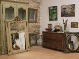 une commode et un miroir dans une pièce où sont accrochés des tableaux au mur
