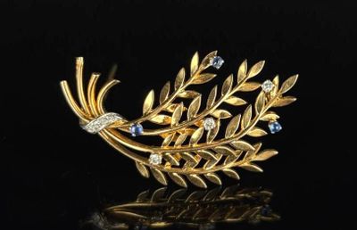 an image of a gold and diamond broochle on a black surface