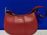 un sac à main en cuir rouge muni d'une poignée en métal, posé sur une table blanche