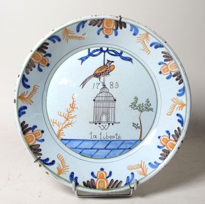 une assiette sur laquelle sont représentés un oiseau et une cage à oiseaux
