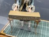 une figurine représentant une femme assise sur un banc