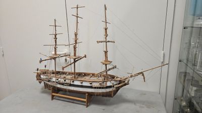 a wooden model of a ship on display in a glass case