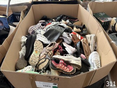 plusieurs paires de chaussures dans une boîte en carton posée sur le sol