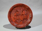 a red plate with a design on it on a stand