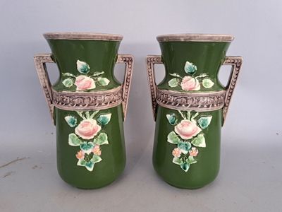 pair of green vases with pink roses on them sitting on a table