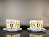 two cups and saucers are sitting on a black table