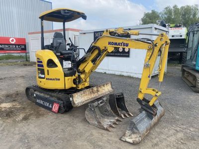 the back end of a small excavator parked in front of a building