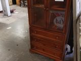 un meuble en bois avec une porte en verre dans une pièce